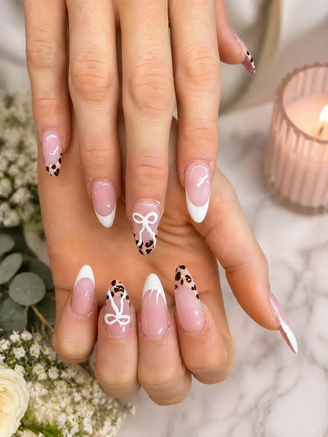 Glossy pink French tip nails with white bow and brown accent nail art