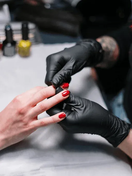 Gloss red polish manicure being finished by a nail technician