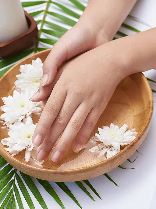 Hands soaking with flowers during a calming salon hand spa ritual