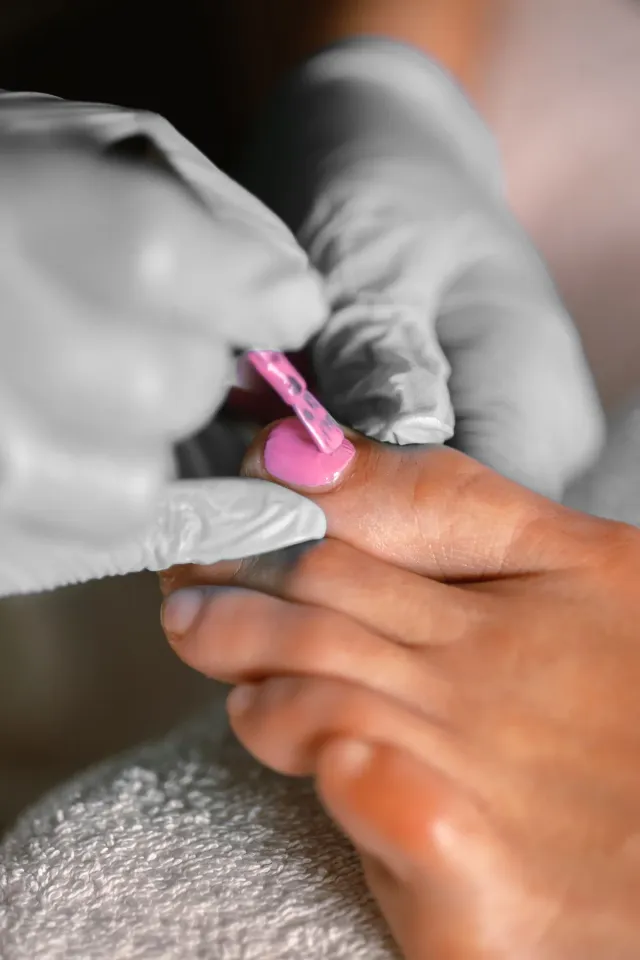 Pink polish being applied to toenails during a salon pedicure