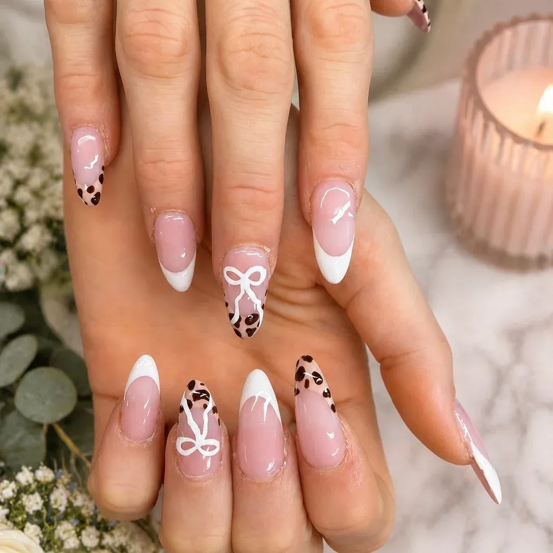 Long pink almond nails with white French tips, leopard print accents and hand-painted white bows