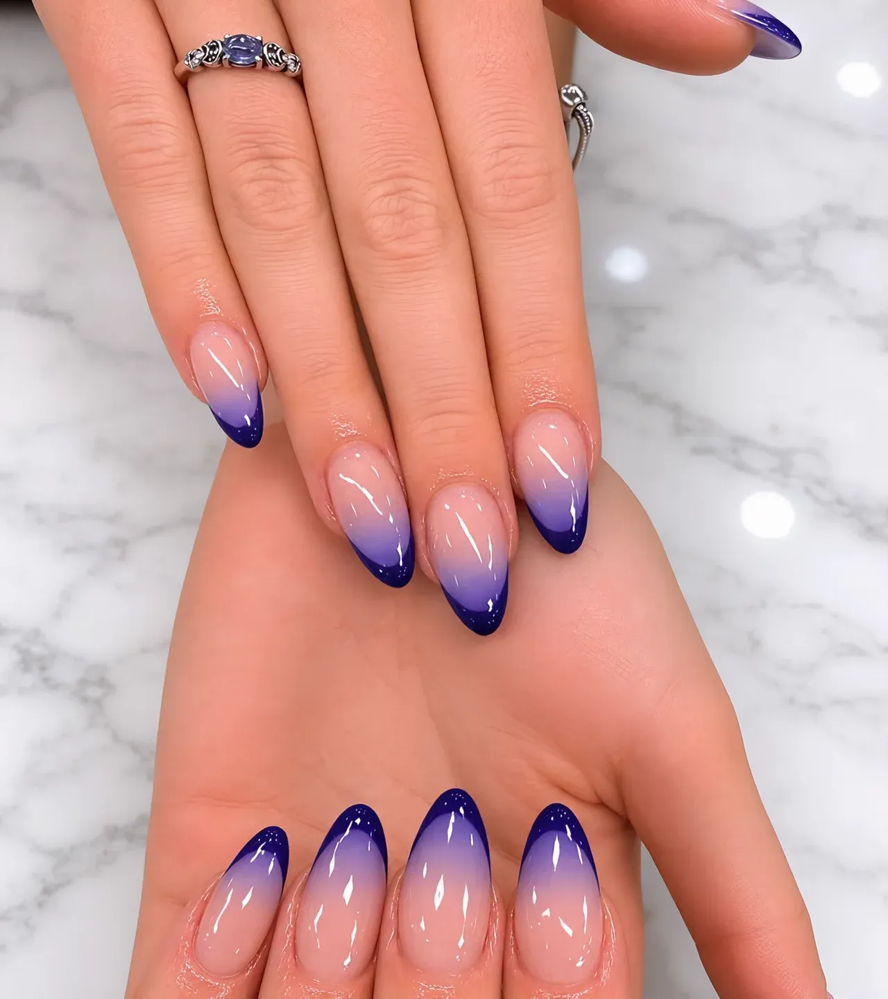 Blue-to-nude ombre almond nails on a marble backdrop