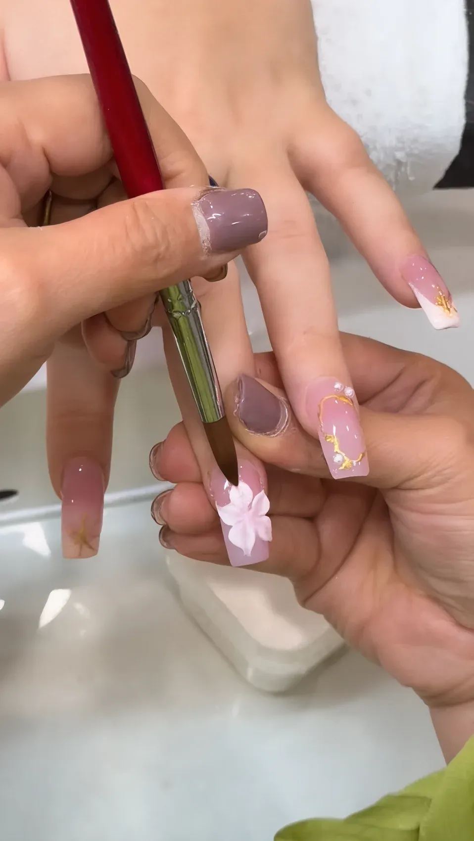 Nail technician hand-painting a delicate 3D flower onto a coffin nail