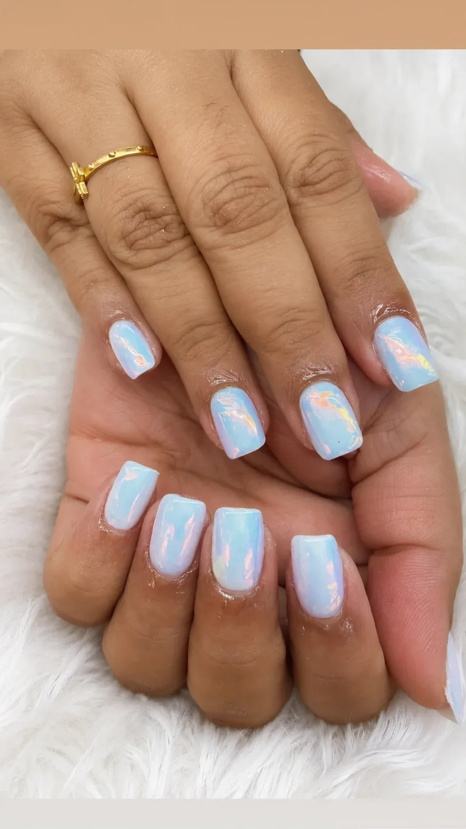 Short square nails in pearly sky-blue chrome on a soft fur backdrop